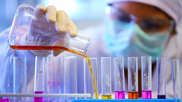 scientist mixing colourful chemicals. chemist experimenting. science experiment in a beaker flask titration with colorful chemicals liquid in laboratory with medical lab equipment. Scientist