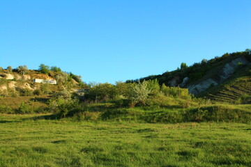 A grassy hill with a house in the distance