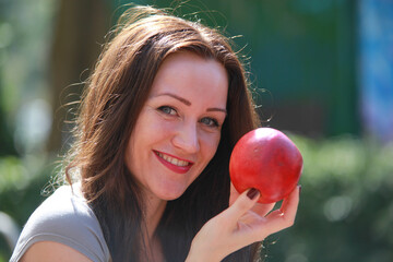Junge Frau mit langen dunklen Haaren und roten Apfel