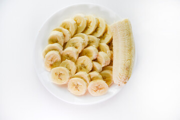 Sliced bananas on a white plate. Delicious and juicy fruits. Breakfast on a plate.
