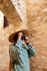 Beautiful woman in a hat takes pictures outdoors using an analog camera. travel to Arab countries.