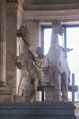 A majestic statue of a man riding a magnificent horse is captured in front of a grand window,...