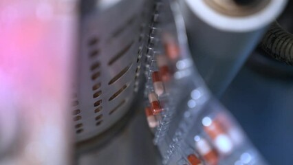 Medicine tablet packing machine close up. machine packaging tablets in blister, alu alu packing. equipment sealing tablets in packets. automatic sealing machine in a pharmaceutical manufacturing.	