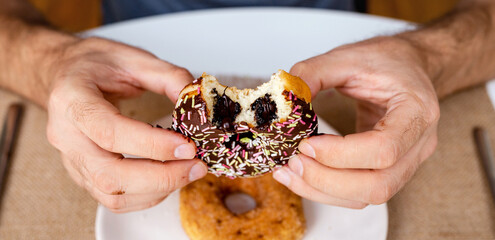 US style donut with chocolate in male's hands closeup.