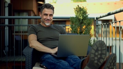 Man working with laptop on balcony