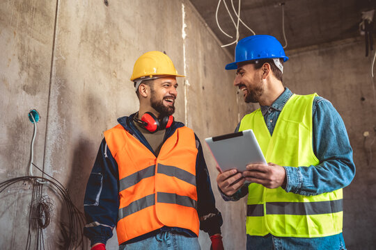 Two construction workers working together on the construction site. Visiting new building and planning new work.