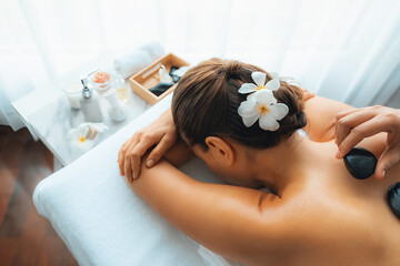 Hot stone massage at spa salon in luxury resort with day light serenity ambient, blissful woman...