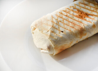 Meat shawarma on a white plate. A meat delicacy. Gyros kebab.