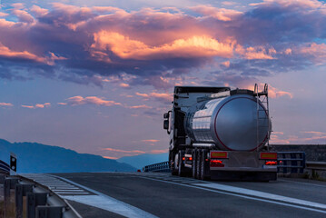 Tanker truck for foodstuffs on a change of grade and with a dramatic sunset sky in the background,...