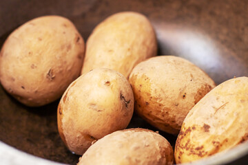 Potatoes, a staple food, are being boiled in a pan with water