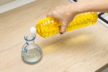 housewife pours sunflower oil into a glass bottle.