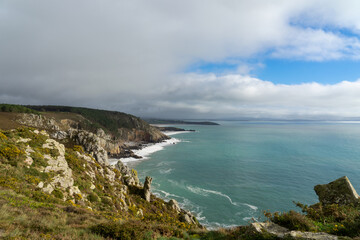Obraz premium Au-dessus des falaises, un grain éphémère assombrit le ciel, laissant entrevoir quelques éclaircies et des nuages flottant au-dessus de la majestueuse mer d'Iroise, un spectacle changeant et captivant