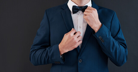 Fixing bowtie, man and hands in suit for professional, salesman or groom in studio. Gentleman, formal fashion and black background for job interview, business and financial advisor in corporate