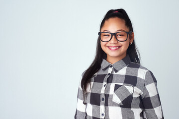 Portrait, girl and kid with glasses, nerd and confident student on blue studio background. Face, happy person and model with smile and eyewear for clear vision, looking and mockup space with geek