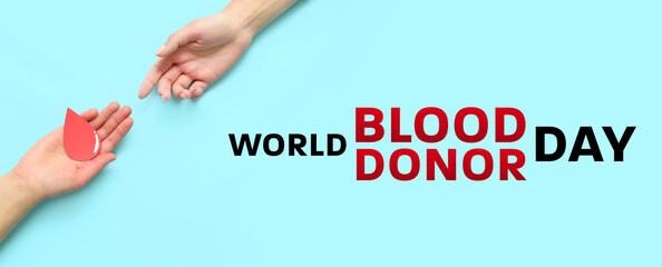 Women with paper blood drop on blue background. World Donor Day