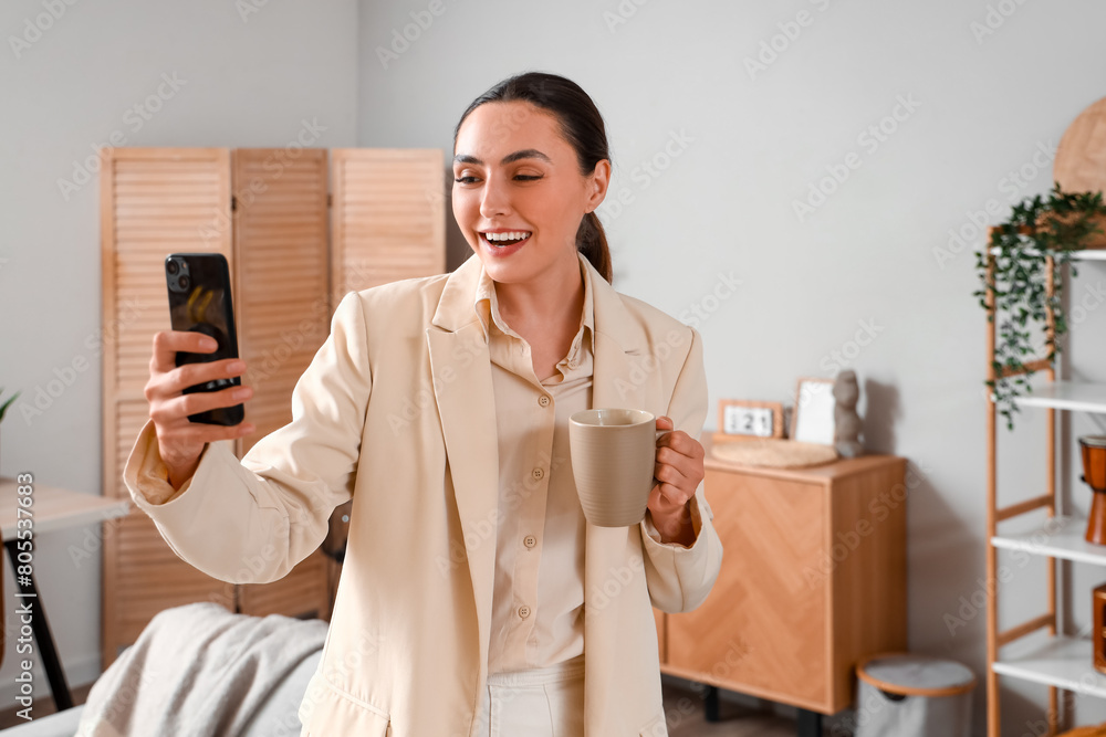 Poster Young businesswoman with mobile phone video chatting at home