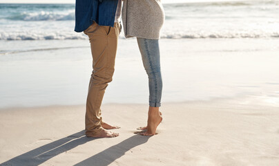 Couple, legs and sand at beach with water for sunshine, holiday romance, love together and...