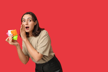 Young gossiping woman with condoms on red background. Safe sex concept