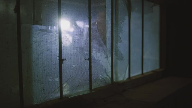 People wearing full protection gear shining flashlights behind a broken window indoors