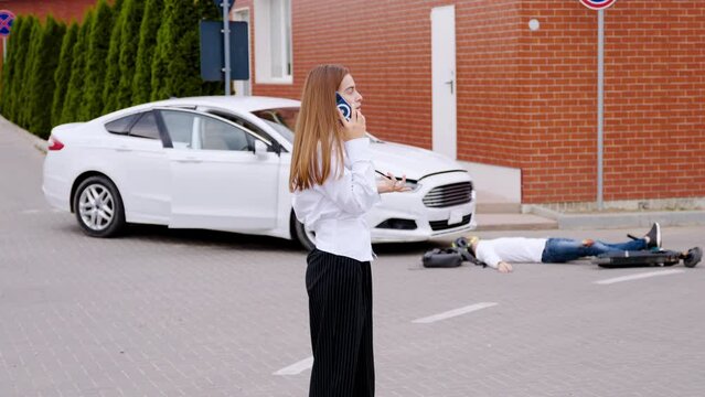 Following car and electric scooter collision female driver contacts emergency services accident. Aftermath of car and electric scooter collision woman calls to emergency services reporting incident.