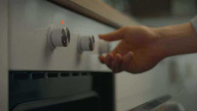 In a home kitchen filled with the aromas of seasonings and fresh ingredients, a man intently sets the timer on the oven so he doesn't miss the moment when his casserole is ready to serve