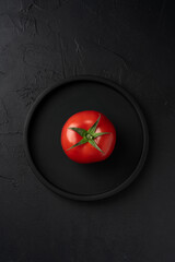 Red and fresh tomato on the black background