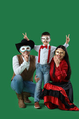 Happy family in costumes and carnival masks on green background