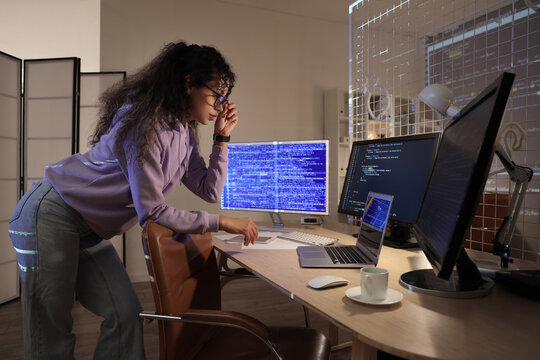 Female African-American programmer working near table in office at night