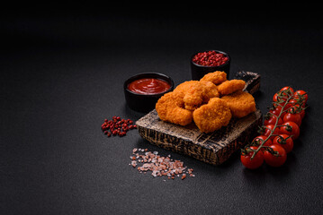 Delicious fresh crispy chicken nuggets on a dark concrete background