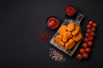 Delicious fresh crispy chicken nuggets on a dark concrete background