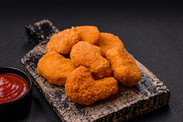 Delicious fresh crispy chicken nuggets on a dark concrete background