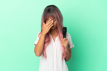 Young mixed race singer woman with pink hair isolated on green background with tired and sick...