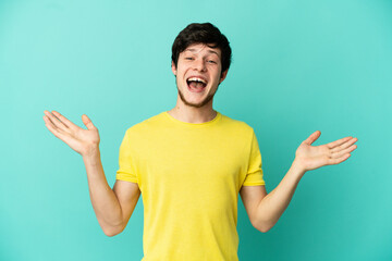 Young Russian man isolated on blue background with shocked facial expression