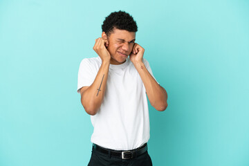 Young African American man isolated on blue background frustrated and covering ears