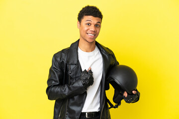 Young African American man with a motorcycle helmet isolated on yellow background with surprise...