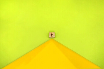 黄色い山のてっぺんに人のシルエットマークのブロックが立つ緑色の背景