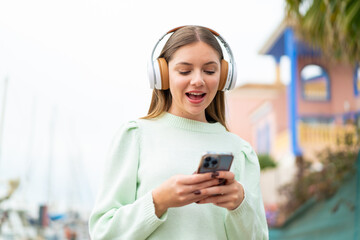 Young pretty blonde woman listening music and looking to mobile