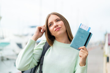 Young pretty blonde woman holding a passport and having doubts