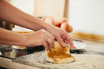 Womans hands kneading dough for cakes on a kitchen table. Prepared easter cake and eggs in a plate on background. Domestic kitchen scene. 