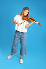 Beautiful woman playing violin on blue background © New Africa