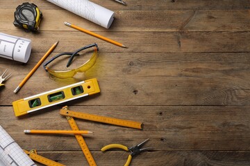 Flat lay composition with building level and other construction tools on wooden table, space for...