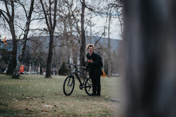 Obraz premium A cheerful business entrepreneur taking a break in the park with his bicycle, engaged on a smart phone.