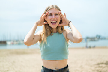 Young blonde woman at outdoors with surprise expression