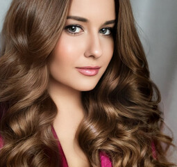 Beautiful woman with curly volume hairstyle, long luxurious hair and beauty make-up, glamorous look...