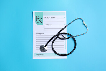 Clipboard with medical prescription form and stethoscope on light blue background, flat lay