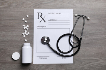Medical prescription form, stethoscope and pills on wooden table, flat lay