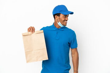 African American man taking a bag of takeaway food isolated on white background looking to the side and smiling