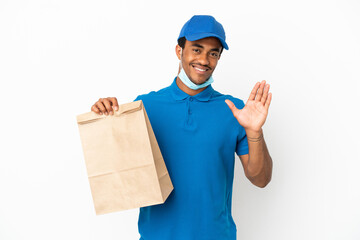 African American man taking a bag of takeaway food isolated on white background saluting with hand...