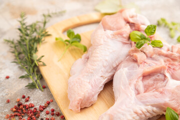 Raw turkey wing on a wooden cutting board on a brown concrete background. Side view, selective focus