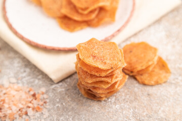 Slices of dehydrated salted meat chips on gray concrete, side view, selective focus